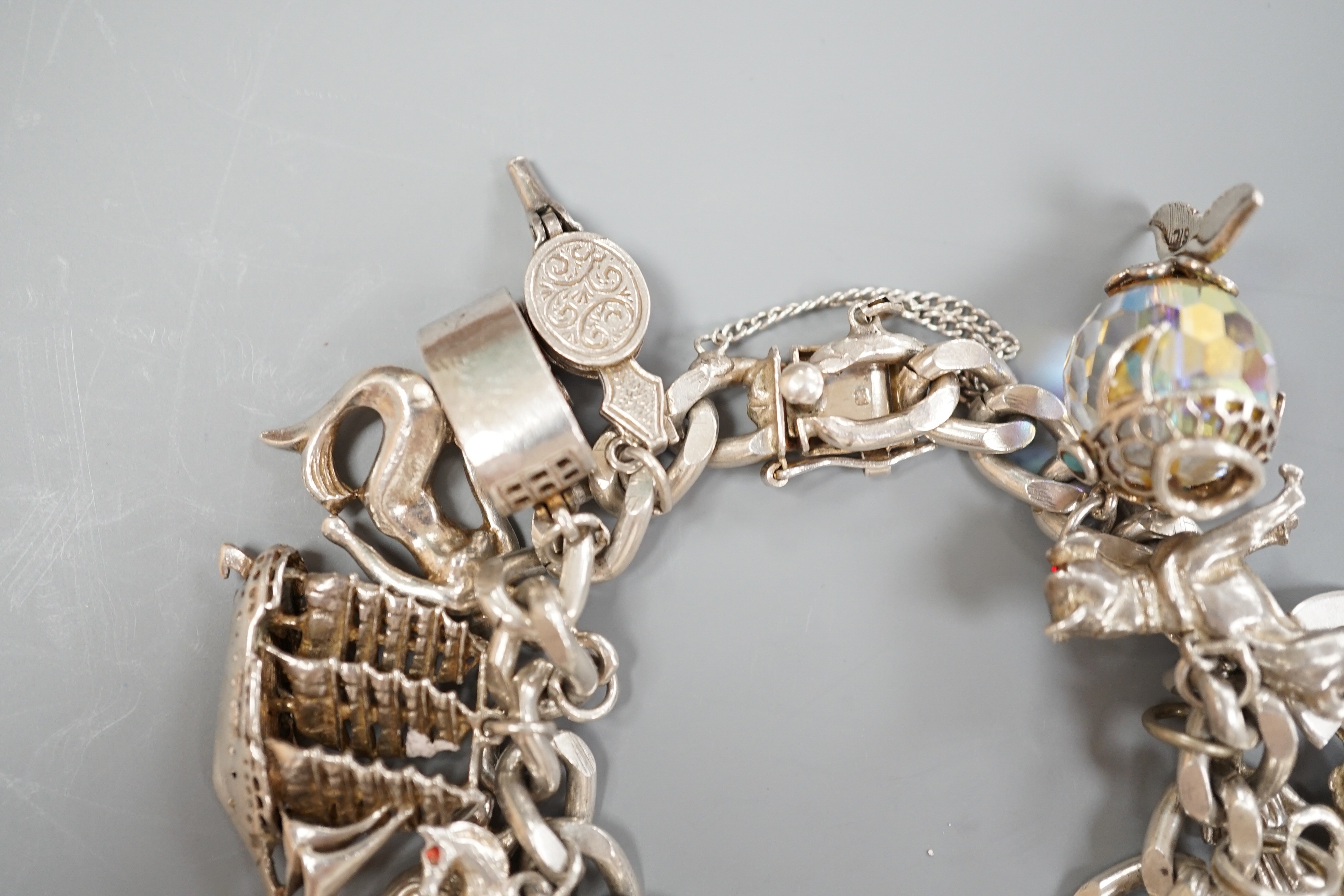 A silver charm bracelet, hung with sixteen assorted charms, gross weight 107.6 grams.